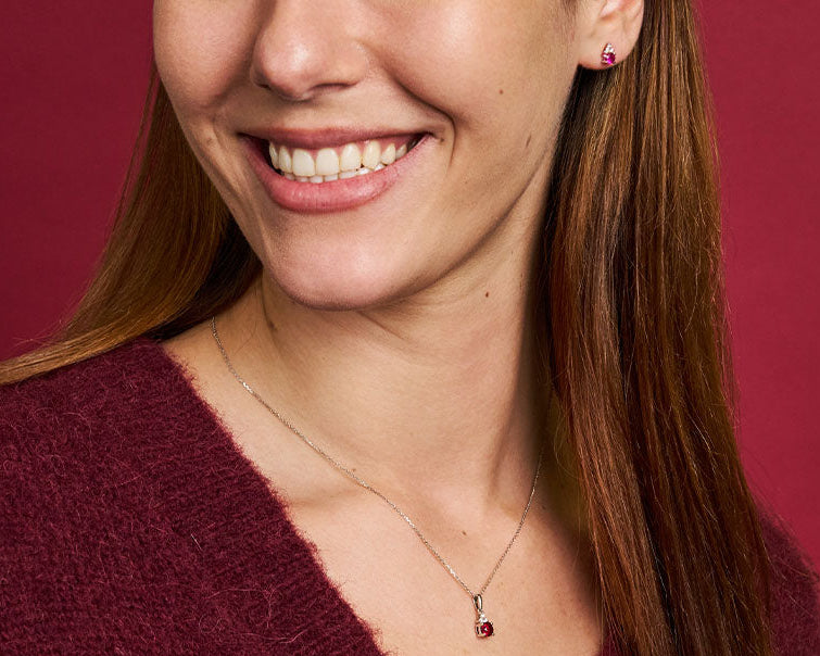 Woman wearing a necklace with a pendant against a red background