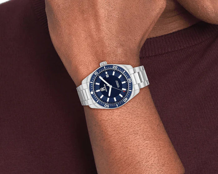 Person wearing a silver watch with a blue face on a white background