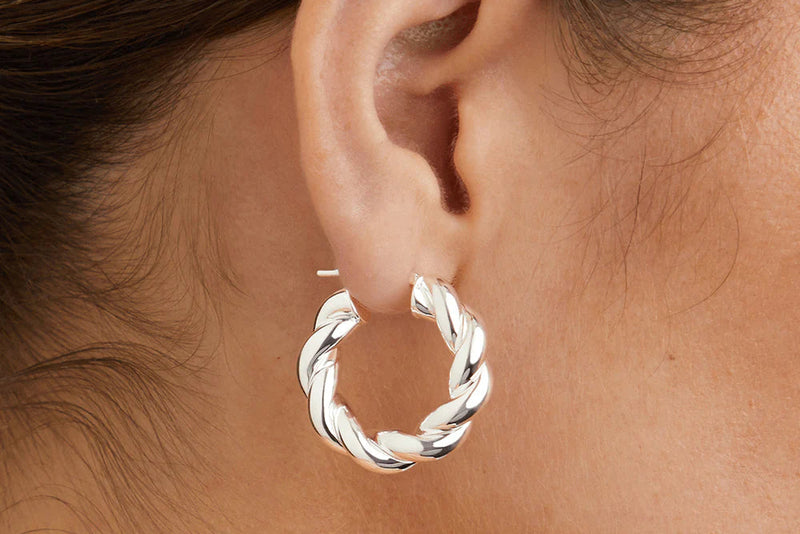 Silver hoop earring worn by a person with hair partially covering the ear.