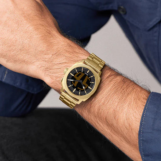 Man wearing a gold watch on his wrist with a neutral background