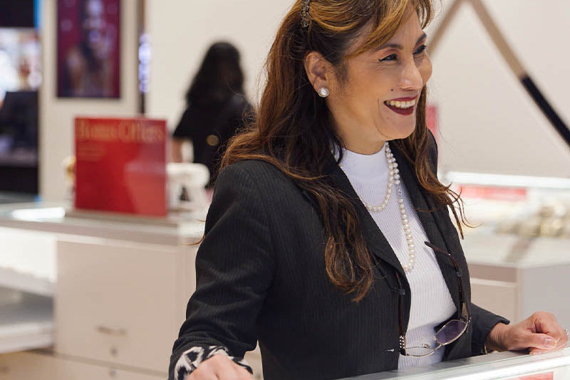 Woman standing behind a counter in a store with jewelry display